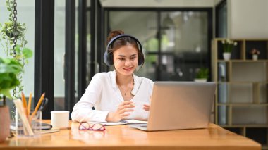 Pretty female student chatting online, listening lecture during study online on laptop. Education, e-learning concept.
