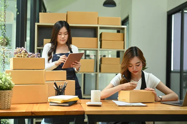 Two young start up business partner working together and preparing parcel boxes of product for shipment.