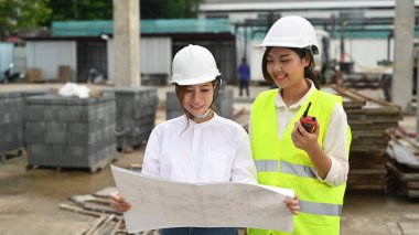 Uzman ekip ve inşaat mühendisi endüstriyel inşaat alanını inceliyor..