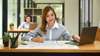 Parlak modern şirket ofisinde dizüstü bilgisayar kullanan güzel bir bayan çalışan..