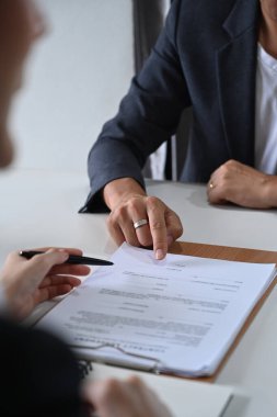 Erkek avukatın müvekkiline hukuki danışmanlık ve hukuki danışmanlık sunarken ve sözleşme belgesinde imzalanacak yeri gösterirken görüntüsü kesilmiş..