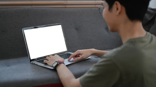 リアビューのアジア人男性のリビングルームに座って 電子メールを読んだり ラップトップコンピュータ上でインターネットサーフィン — ストック写真