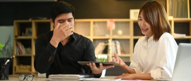 Dijital tableti işaret eden neşeli yaratıcı kadın. Şirket ofisindeki meslektaşıyla yeni bir proje üzerinde çalışıyor..