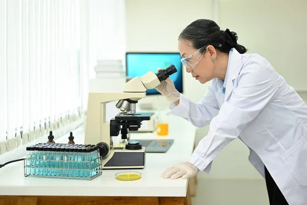 高级女性生物技术专家在显微镜下观察 在实验室进行实验 — 图库照片