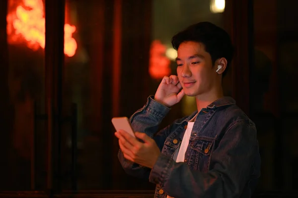 Uomo Hipster Utilizzando Telefono Cellulare Mentre Piedi Sotto Luce Neon — Foto Stock