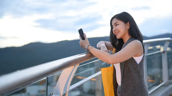 Усміхнена Молода Жінка Друкує Текстове Повідомлення Мобільному Телефоні Стоячи Терасі — стокове фото