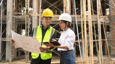 Genç mimarlardan oluşan ekip planlara bakıyor, endüstriyel inşaat alanlarını inceliyor..
