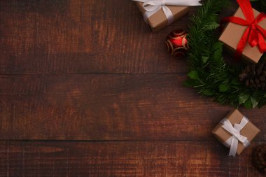 Düz yerde Noel hediyeleri kutuları, ağaç dalları ve tahta arka planda çam kozalakları vardı. Noel arkaplanı kavramı.