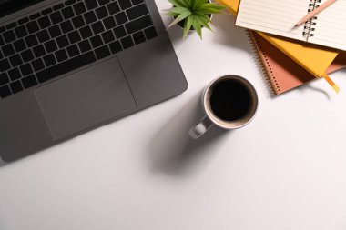 Dizüstü bilgisayar, defter, bir fincan kahve ve gözlük beyaz ofis masasında. Üst Manzara, Şişko..