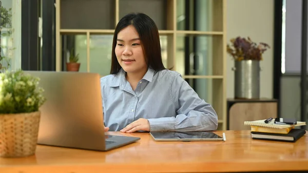 アジアの女性従業員がノートパソコンで情報をチェックし 企業のオフィスに座って — ストック写真