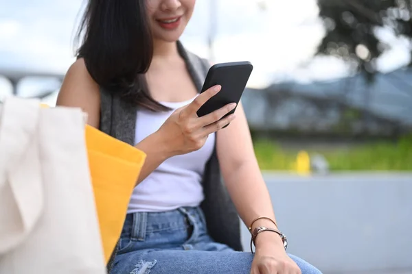 年轻女子坐在公园的长椅上 通过智能手机在社交网络中进行交流 — 图库照片