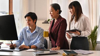 Genç yaratıcı insanlar ve yaşlı kadın proje yöneticisi birlikte mobil uygulama yazılım tasarımı projesinde beyin fırtınası yapıyorlar..