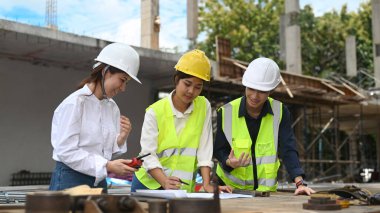 Mühendisler, yöneticiler ve inşaat işçileri inşaat alanında plan detaylarını tartışıyor..