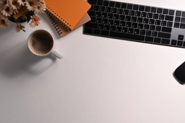 Kablosuz klavyeli beyaz ofis masası, bir fincan kahve ve defter. Metin için alanı kopyala.