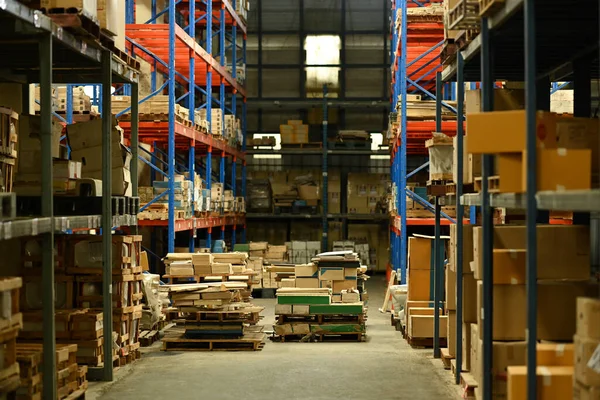 Interior of large logistic distribution warehouse full of shelves with goods in cardboard boxes and pallets.