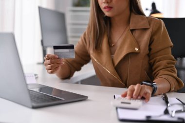 Hesap makinesi kullanan ve internette ödeme yapan zarif genç bir kadın. Çevrimiçi alışveriş, e-ticaret kavramı.