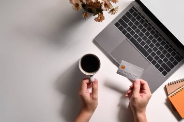 Laptop bilgisayarının önünde elinde kredi kartı olan bir adamın tepeden görünüşü. Çevrimiçi alışveriş, e-ticaret kavramı.