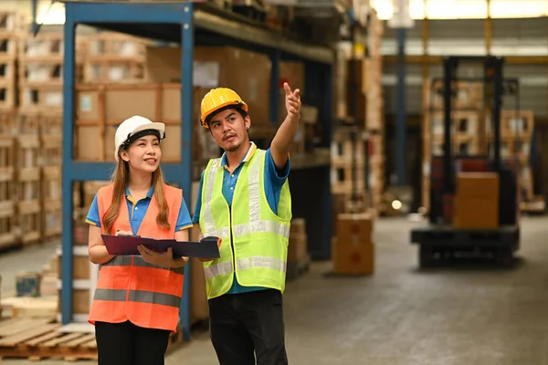 Depo çalışanı, raflarla dolu perakende deposunun arasında dururken tabletin detaylarını kontrol ediyor..