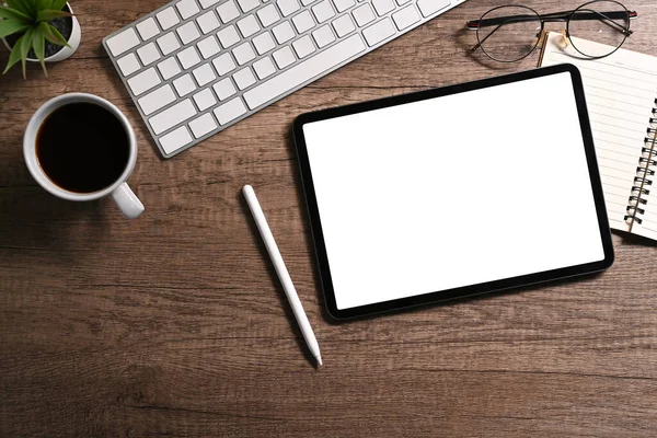 Modern workplace, digital tablet, stylus pen, coffee cup and notebook on wooden table. Top view, Flat lay.