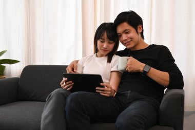 Mutlu genç çift evde ve dijital tablette vakit geçirmekten zevk alıyor. İnsanlar, teknoloji ve yaşam tarzı kavramı.