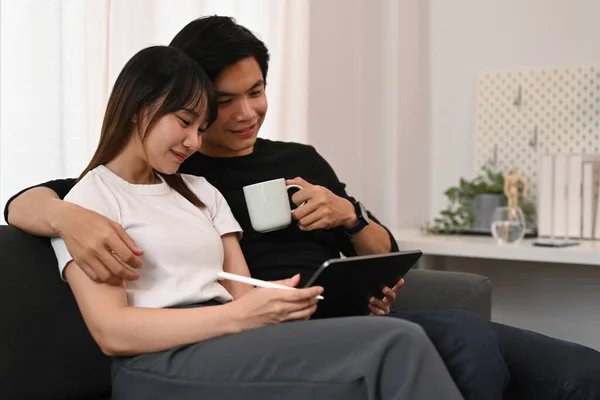快適なソファでデジタルタブレットを採用し 使用して若いカップルを愛しています 人と技術の概念 — ストック写真