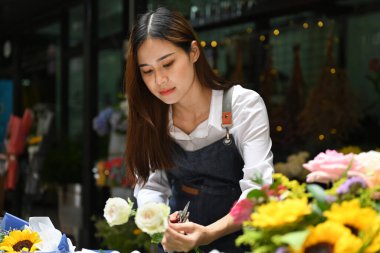 Çiçekçi önlük takıyor, çiçek buketi yapıyor, süslemeler yapıyor ve çiçek stüdyosunu düzenliyor..