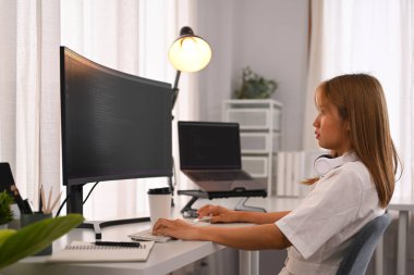 Genç bayan programcı, modern ofisteki masaüstü bilgisayarında şifreli verilerle çalışıyor..