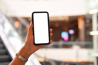 Kadının el ele tutuşması, bulanık yürüyen merdivene karşı akıllı telefon taklidi yapıyor. Reklam metniniz için boş ekran. 