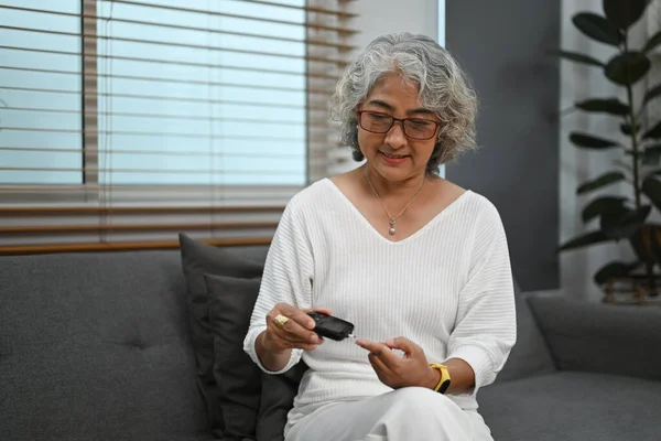 老年糖尿病妇女在家里用血糖表检查血糖水平 糖尿病 保健概念 — 图库照片