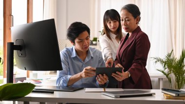 Bir grup iş adamı dijital masaya bakıyor ve şirket ofisinde iş planı pazarlama stratejisini tartışıyorlar..