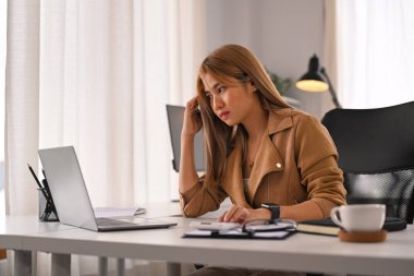 Yorgun kadın ofis çalışanı başını tutuyor, baş ağrısı çekiyor, aşırı çalışmaktan ya da iş stresinden yorgun düşmüş..