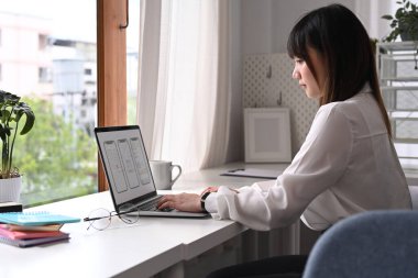 Bilgisayar ekranında cep telefonu prototipi için çalışan Asyalı genç kadın web geliştiricisinin yan görünümü.