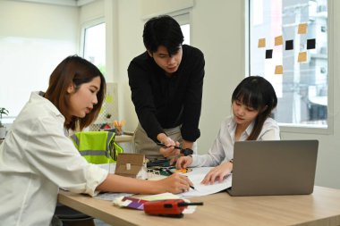Mimarlar takımı beyin fırtınası yapıyor, toplantı odasında inşaat planları üzerinde birlikte çalışıyorlar.. 