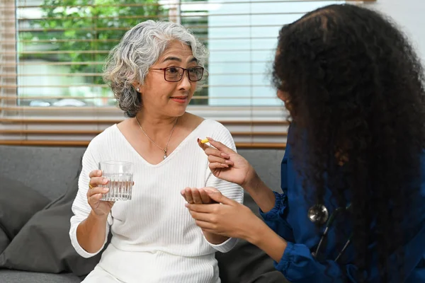 高齢患者への薬の投与量を説明する女性看護師の画像 高齢者医療と在宅医療サービスの概念 — ストック写真