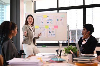 Kendine güvenen genç bayan proje yöneticisi yeni proje fikrini ya da kurumsal iş planını toplantıda açıklıyor.