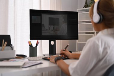 Modern iş yerinde renk örnekleri ve bilgisayarla çalışan genç yaratıcı kadının arka görünüşü.