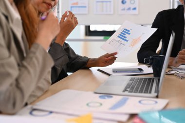 Şirket işletme ekibi ve yönetici finansal verileri analiz ediyor, toplantı masasında dizüstü bilgisayar kullanıyor..