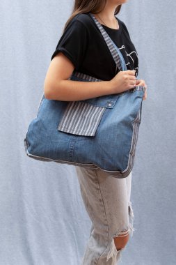 Bir kız elinde doğal kumaştan yapılmış tekrar kullanılabilir bir Eko Poşet tutuyor.