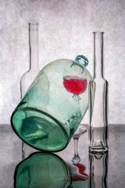 Bir cam kavanoz, bir bardak kırmızı şarap ve iki şişe