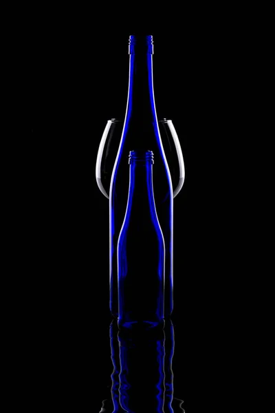 黒を背景に青いボトルとガラスの静物画 — ストック写真