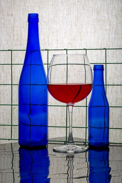 Stillleben Mit Blauen Flaschen Und Einem Glas Rotwein — Stockfoto