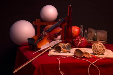 Keman ve kırmızı masada farklı objelerle dolu bir hayat.