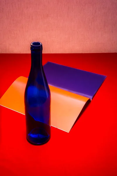 青いボトルと赤いテーブルの上に色のシートが付いているノートブックでまだ生活 — ストック写真