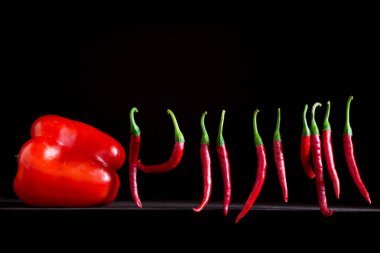 Siyah arka planda kırmızı tatlı biber ve keskin biberlerle dolu bir hayat