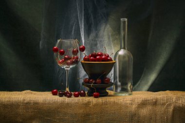 Still life with ripe cherries in a glass and vase
