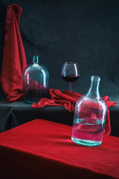 Still life with glass jars and a glass of wine