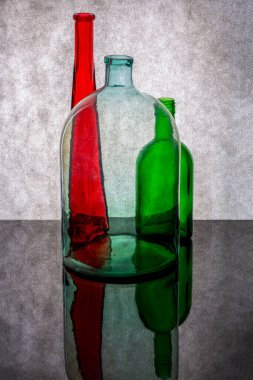 Still life with colored glass bottles and a jar