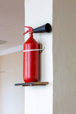 Portable hand-held fire extinguisher mounted on the wall inside the room