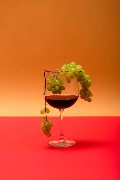 Бокал Красного Вина Гроздь Винограда Цветном Фоне — стоковое фото