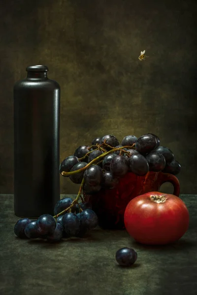 Still life with grapes, tomatoes, a dark bottle and a bee